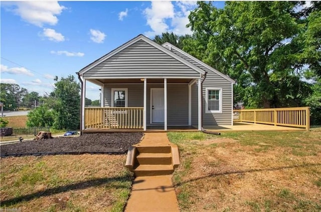 bungalow featuring a porch, fence, and a front lawn