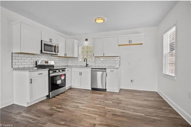 kitchen with dark wood finished floors, white cabinetry, stainless steel appliances, decorative backsplash, and baseboards