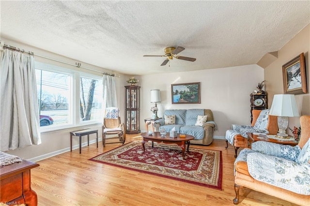 living room with hardwood / wood-style flooring, ceiling fan, a textured ceiling, and vaulted ceiling