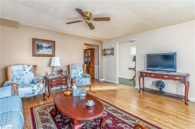 living room featuring hardwood / wood-style floors, ceiling fan, and a textured ceiling