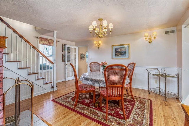 dining room featuring hardwood / wood-style floors, a textured ceiling, and a chandelier