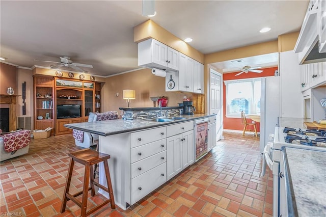 kitchen featuring a kitchen bar, white cabinetry, dishwasher, and sink