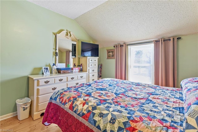 bedroom featuring a textured ceiling, light wood-type flooring, and vaulted ceiling