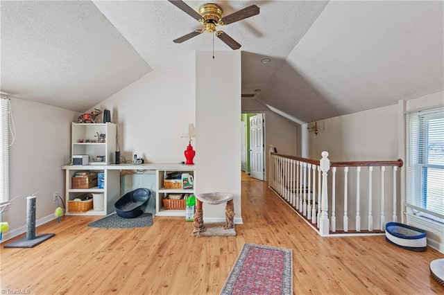 interior space featuring a textured ceiling, ceiling fan, hardwood / wood-style floors, and vaulted ceiling