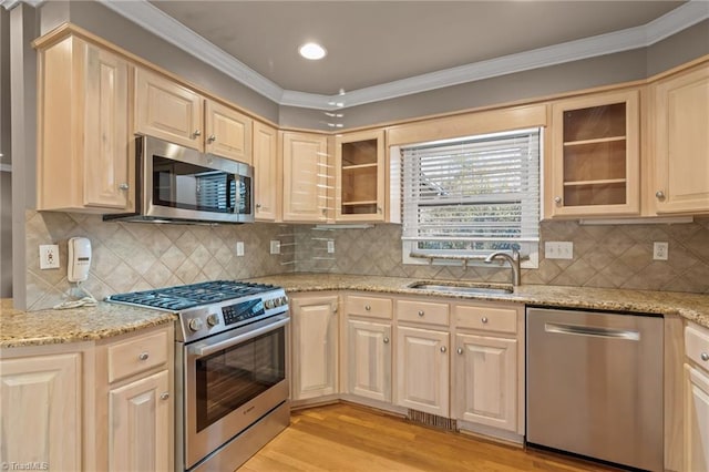 kitchen with backsplash, sink, light stone countertops, and stainless steel appliances