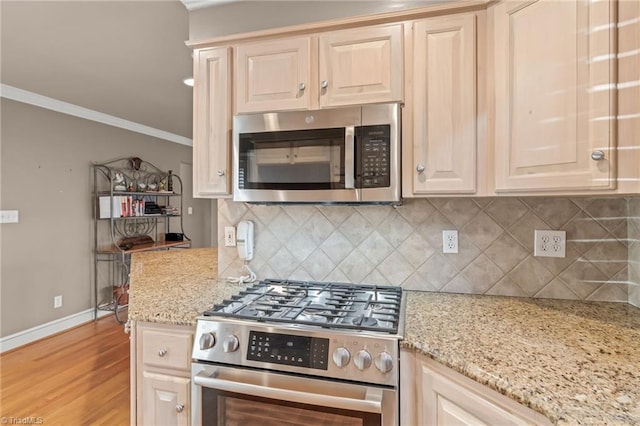 kitchen with light stone countertops, stainless steel appliances, tasteful backsplash, light hardwood / wood-style floors, and ornamental molding