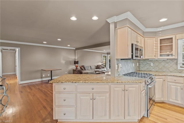 kitchen with light stone countertops, stainless steel appliances, kitchen peninsula, decorative backsplash, and ornamental molding