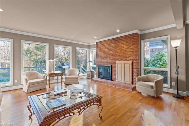 living room with light hardwood / wood-style floors, a brick fireplace, and crown molding