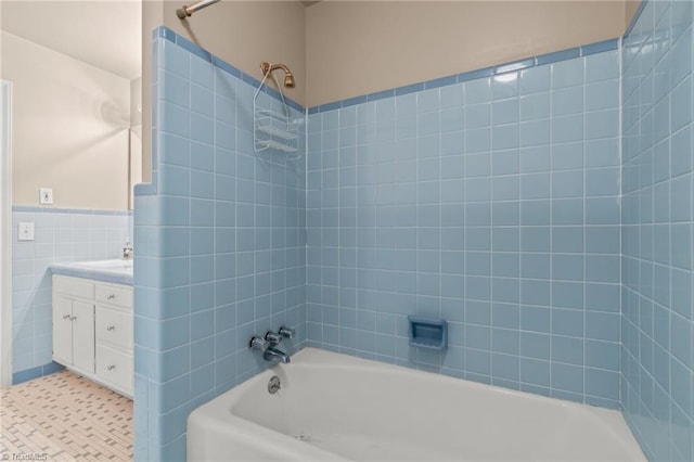 bathroom featuring washtub / shower combination, vanity, and tile walls