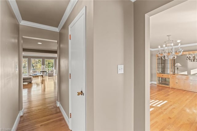 hall featuring a chandelier, hardwood / wood-style flooring, and crown molding