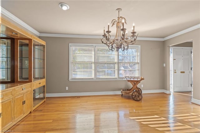 dining space featuring light hardwood / wood-style floors, ornamental molding, and an inviting chandelier