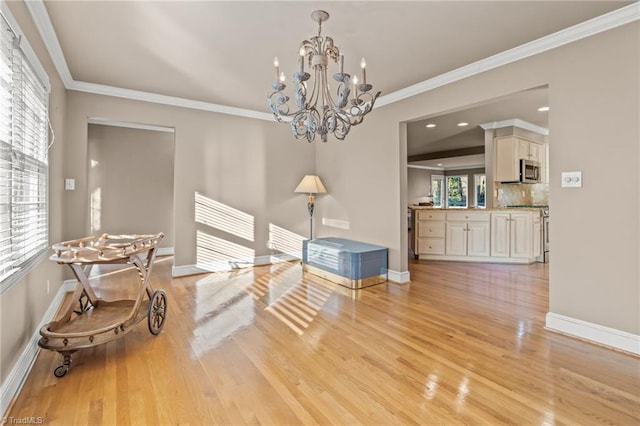 dining room featuring a notable chandelier, crown molding, a wealth of natural light, and light hardwood / wood-style flooring