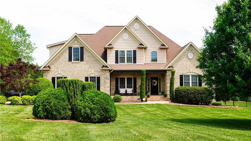 craftsman house featuring a porch, brick siding, and a front yard