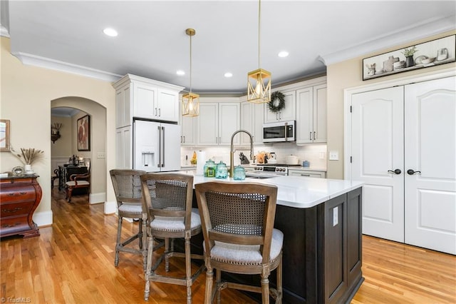 3303 Tanner Ct, Summerfield, NC 27358 - kitchen with ornamental molding, a kitchen bar, arched walkways, light countertops, and high end white fridge