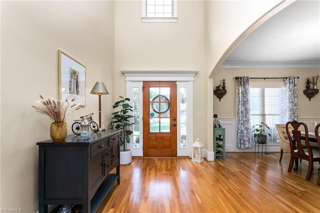 3303 Tanner Ct, Summerfield, NC 27358 - entryway featuring arched walkways, light wood-style floors, a wainscoted wall, and a towering ceiling