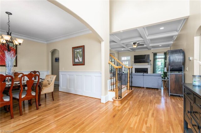 3303 Tanner Ct, Summerfield, NC 27358 - dining space featuring ceiling fan with notable chandelier, a fireplace, arched walkways, light wood-style floors, and stairs