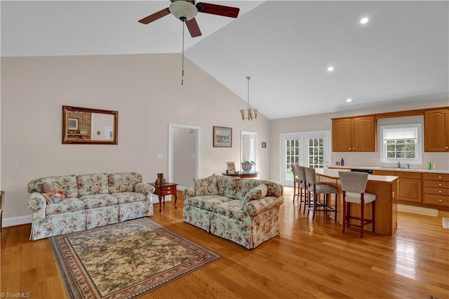 living room featuring ceiling fan, high vaulted ceiling, and light hardwood / wood-style flooring