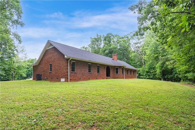 rear view of property with central air condition unit and a lawn