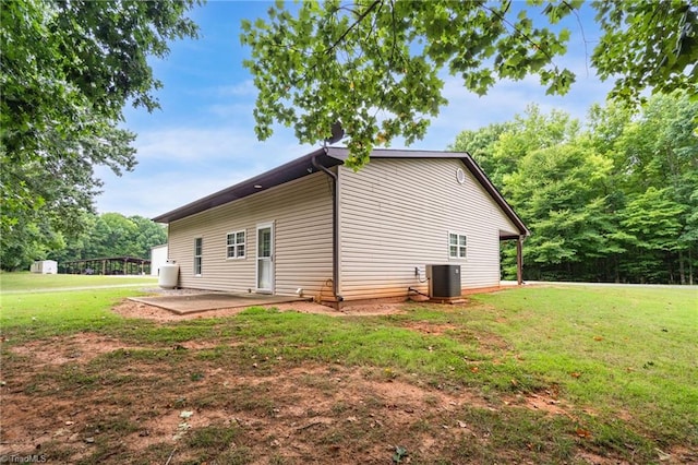 view of side of home featuring central air condition unit, a patio, and a lawn