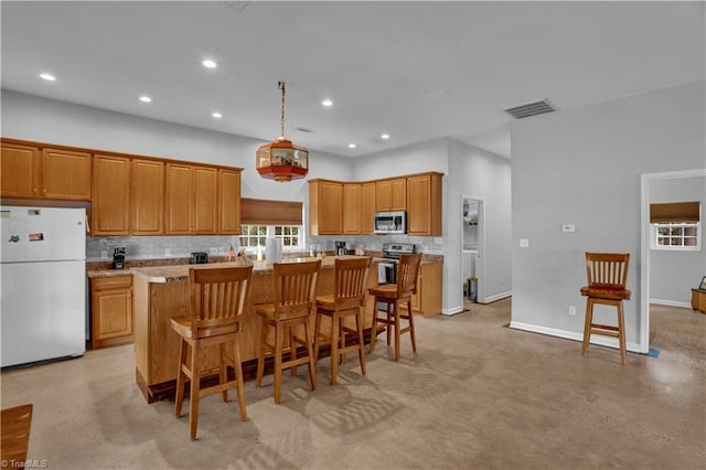 kitchen with a kitchen breakfast bar, white refrigerator, decorative backsplash, a kitchen island, and pendant lighting