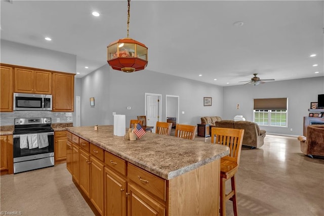 kitchen featuring ceiling fan, decorative backsplash, a breakfast bar, a center island, and stainless steel appliances