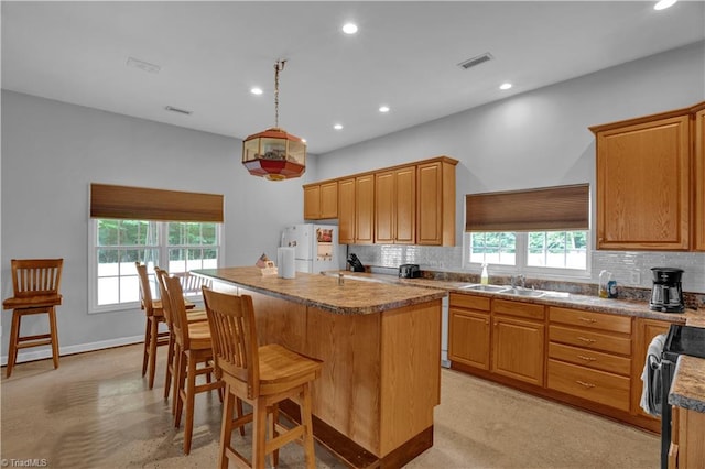 kitchen featuring sink, a center island, decorative backsplash, and white fridge