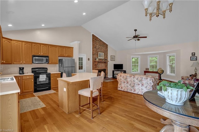 kitchen featuring tasteful backsplash, a brick fireplace, light hardwood / wood-style floors, and stainless steel appliances