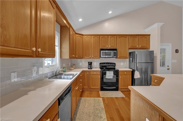 kitchen with appliances with stainless steel finishes, light hardwood / wood-style flooring, tasteful backsplash, sink, and vaulted ceiling