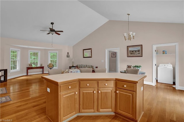 kitchen with ceiling fan with notable chandelier, washer / clothes dryer, light hardwood / wood-style floors, and a kitchen island