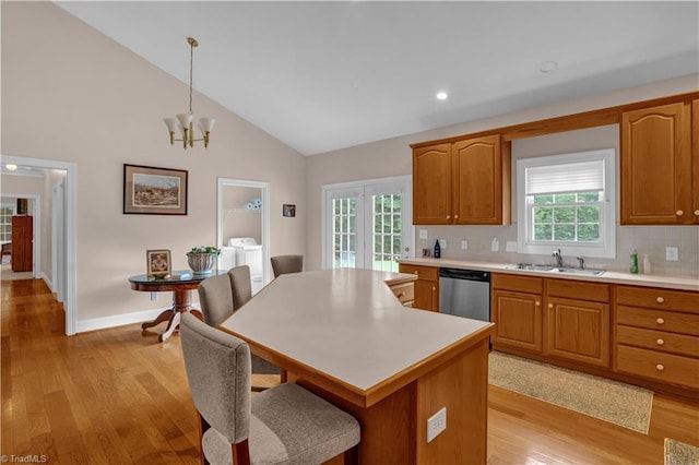 kitchen with sink, light wood-type flooring, tasteful backsplash, dishwasher, and pendant lighting