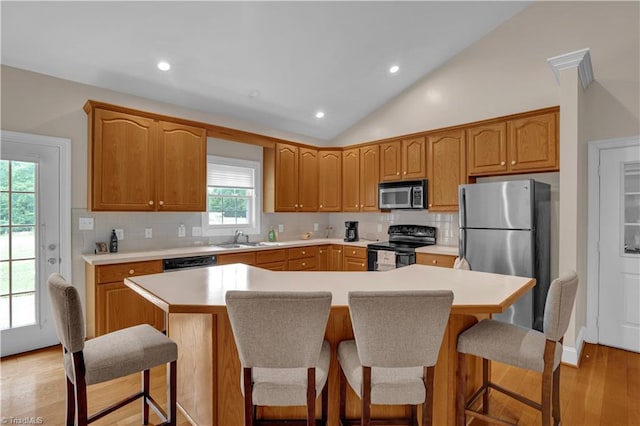 kitchen with light hardwood / wood-style flooring, tasteful backsplash, vaulted ceiling, appliances with stainless steel finishes, and sink