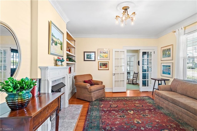 living room featuring wood finished floors, french doors, an inviting chandelier, crown molding, and a premium fireplace