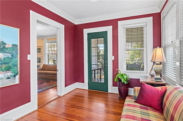 foyer entrance with crown molding, baseboards, and wood finished floors