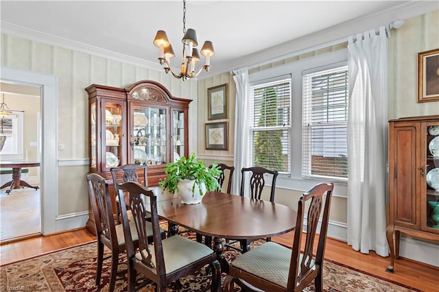 dining area with a notable chandelier, a healthy amount of sunlight, light wood-style flooring, and crown molding