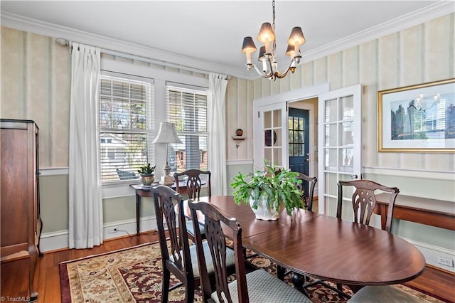 dining area featuring a notable chandelier, crown molding, baseboards, and wood finished floors