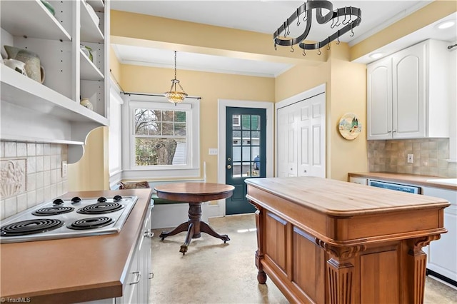 kitchen featuring tasteful backsplash, stainless steel electric cooktop, white cabinets, and crown molding