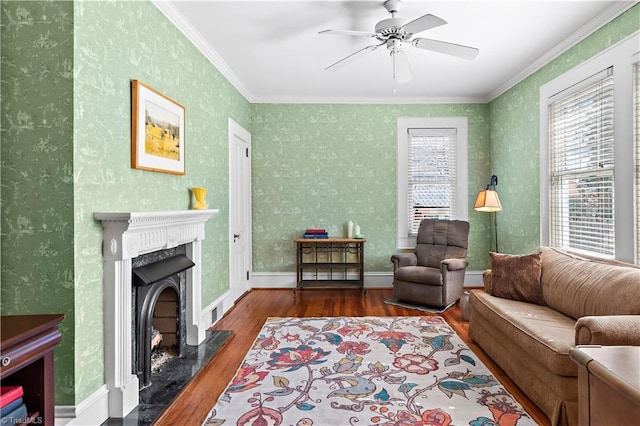 living area featuring a high end fireplace, wallpapered walls, baseboards, ornamental molding, and wood finished floors