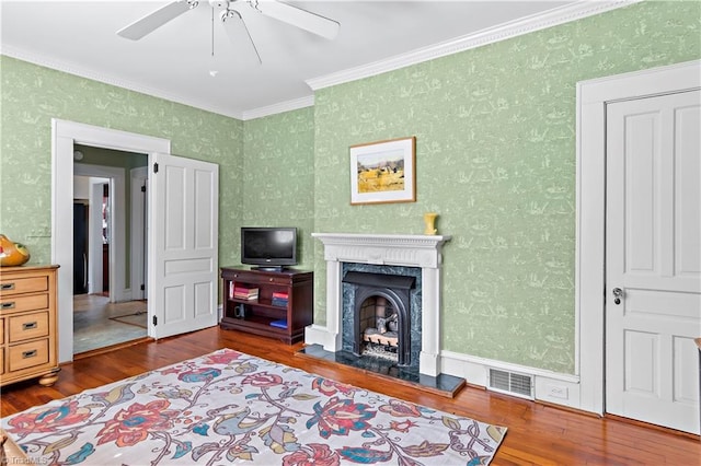 interior space with visible vents, a premium fireplace, wallpapered walls, wood-type flooring, and crown molding