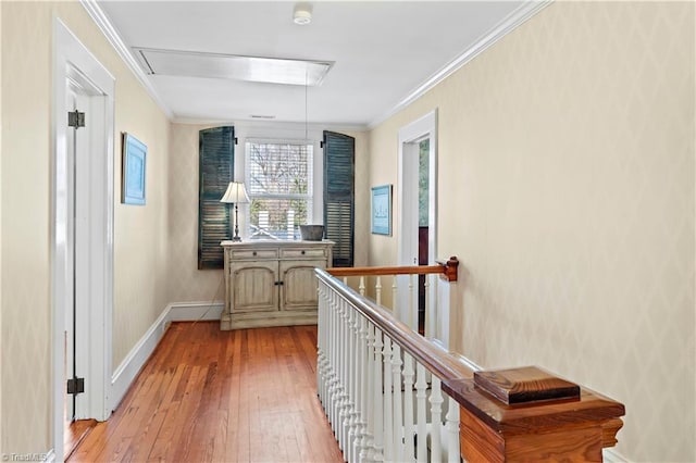 hallway with an upstairs landing, attic access, crown molding, and light wood finished floors