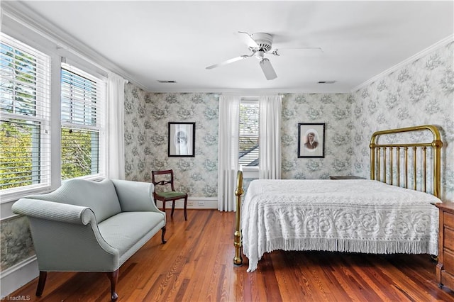 bedroom featuring visible vents, wallpapered walls, crown molding, baseboards, and wood finished floors