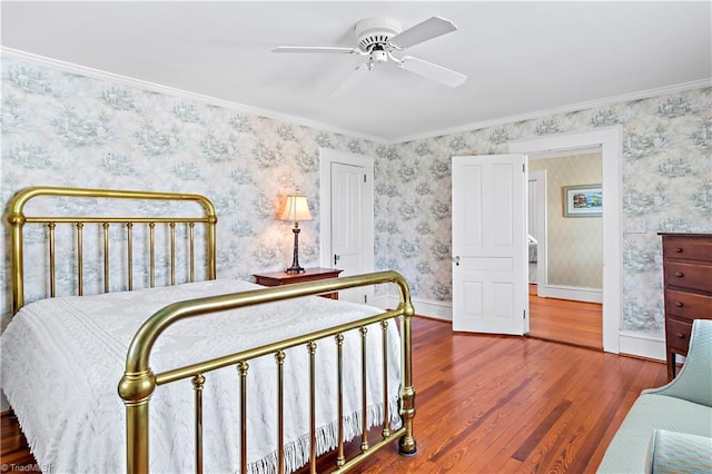 bedroom featuring wallpapered walls, crown molding, wood finished floors, and baseboards