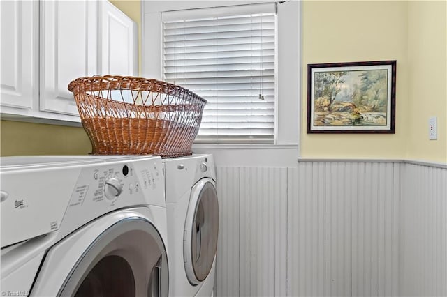 washroom featuring washing machine and clothes dryer, cabinet space, and wainscoting