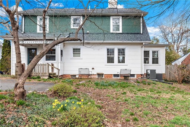 back of property with a chimney, roof with shingles, central AC, and fence