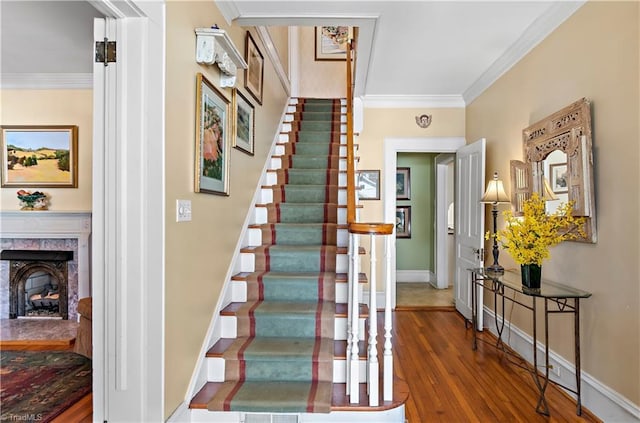 stairs featuring a fireplace, crown molding, wood finished floors, and baseboards