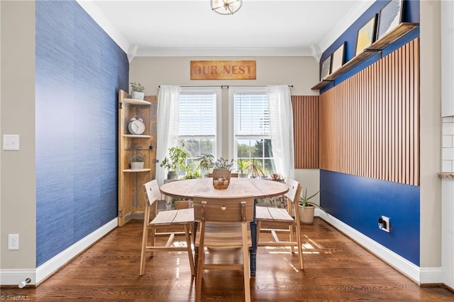 dining room featuring baseboards, an accent wall, wood finished floors, and crown molding