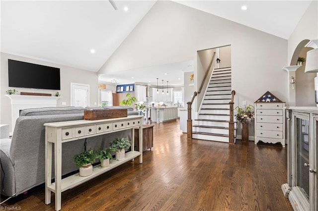 living room featuring high vaulted ceiling, dark wood finished floors, recessed lighting, and stairway