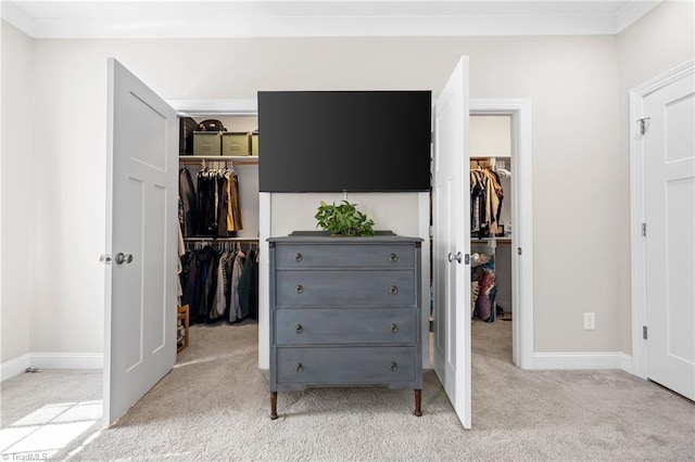 carpeted bedroom with a closet, a spacious closet, and baseboards