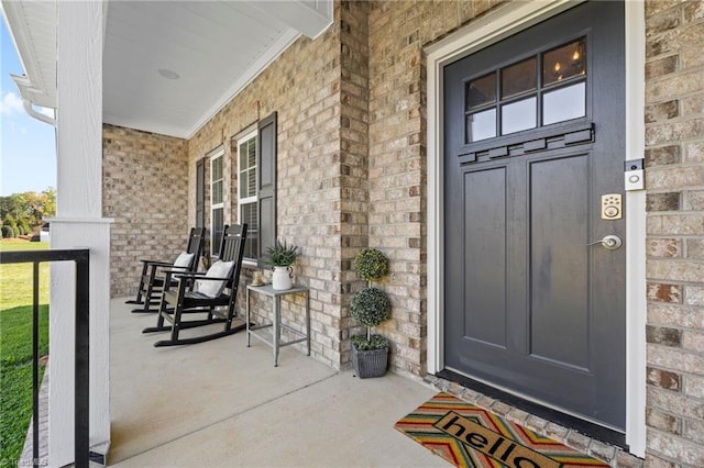 entrance to property featuring brick siding and covered porch