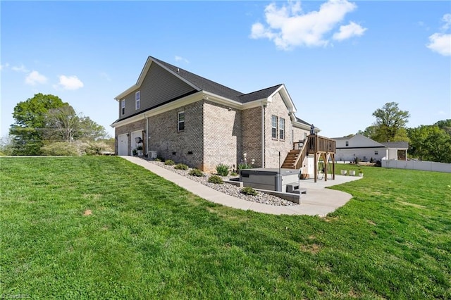 rear view of house featuring an attached garage, fence, a yard, brick siding, and stairs