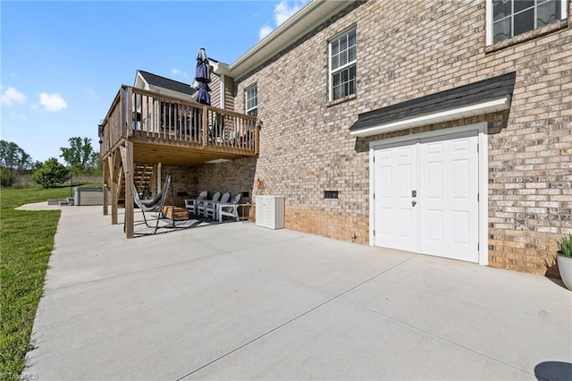 rear view of house featuring a patio, brick siding, and a deck